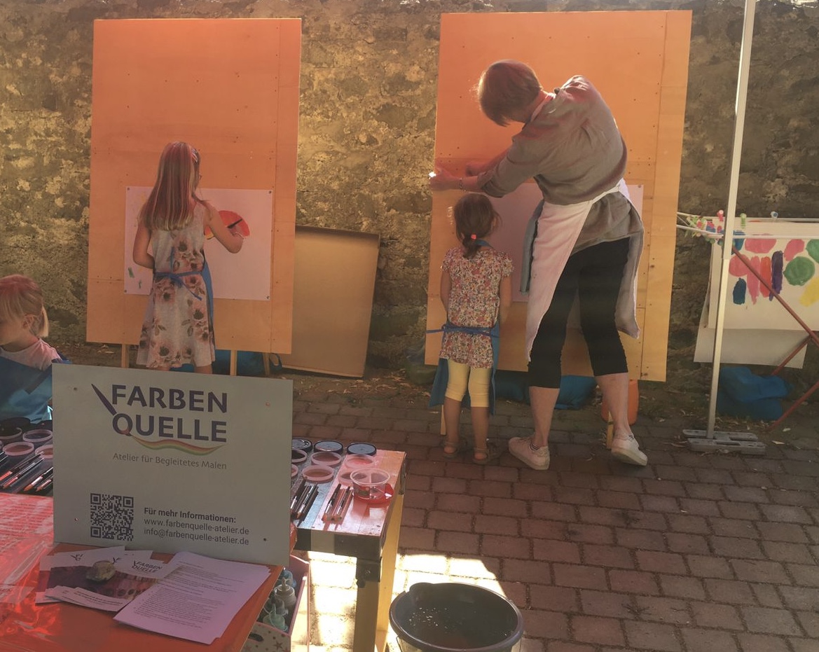 Pinsel im Vordergrund. Ein buntes Bild im Hintergrund